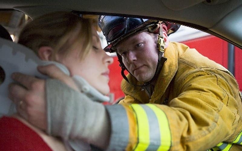 firefighter helping out woman in a car accident with neck