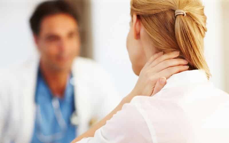 woman holding neck at doctors office