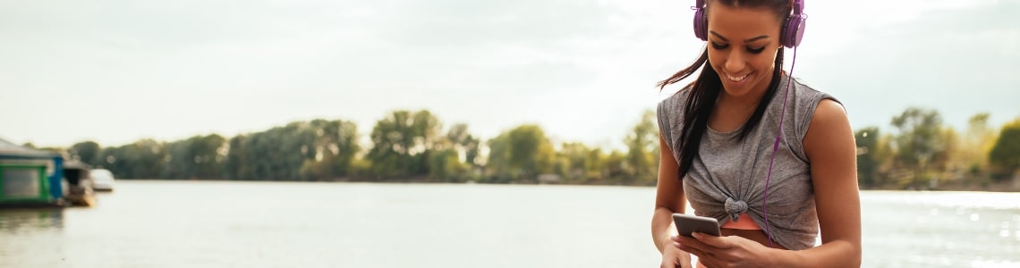 woman choosing music on a run in front of water