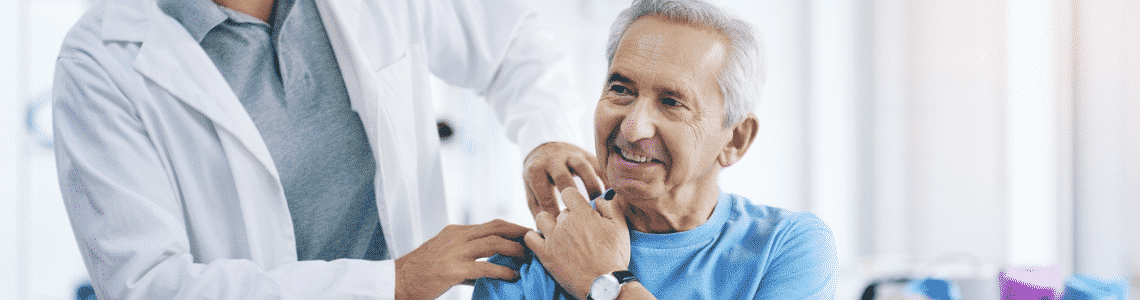 A older man having his shoulder examined by a doctor