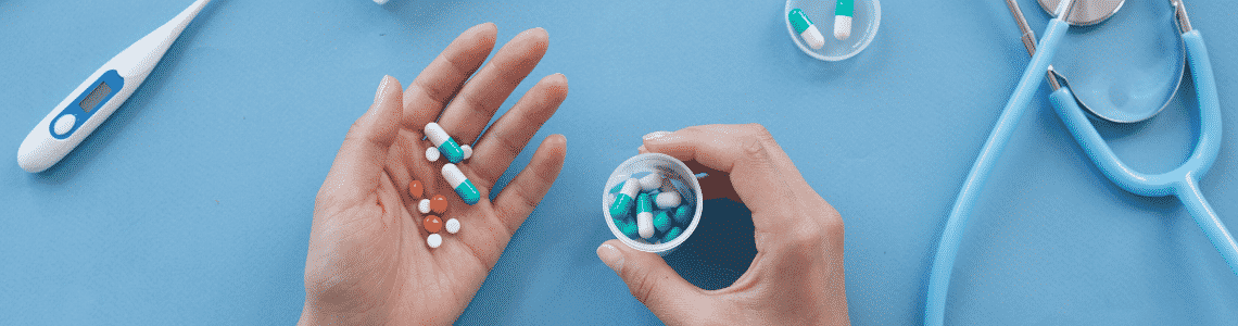 cut of pills and hand holding those pills