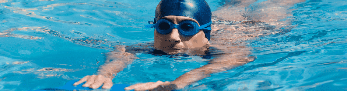 A swimmer swimming in a pool with goggles and a swim cap on