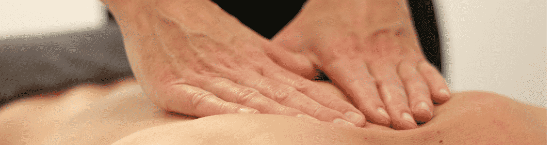 Two hands giving a massage to a woman laying down