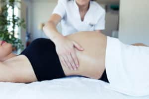 Close-up of female physiotherapist massaging tummy on pregnant woman