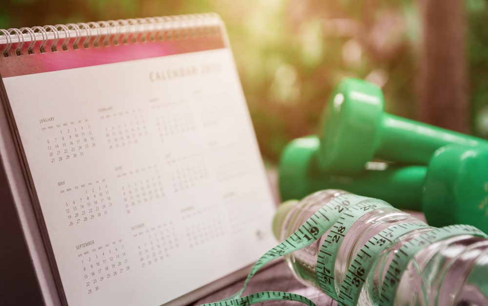 Calendar and equipment fitness on wooden table.