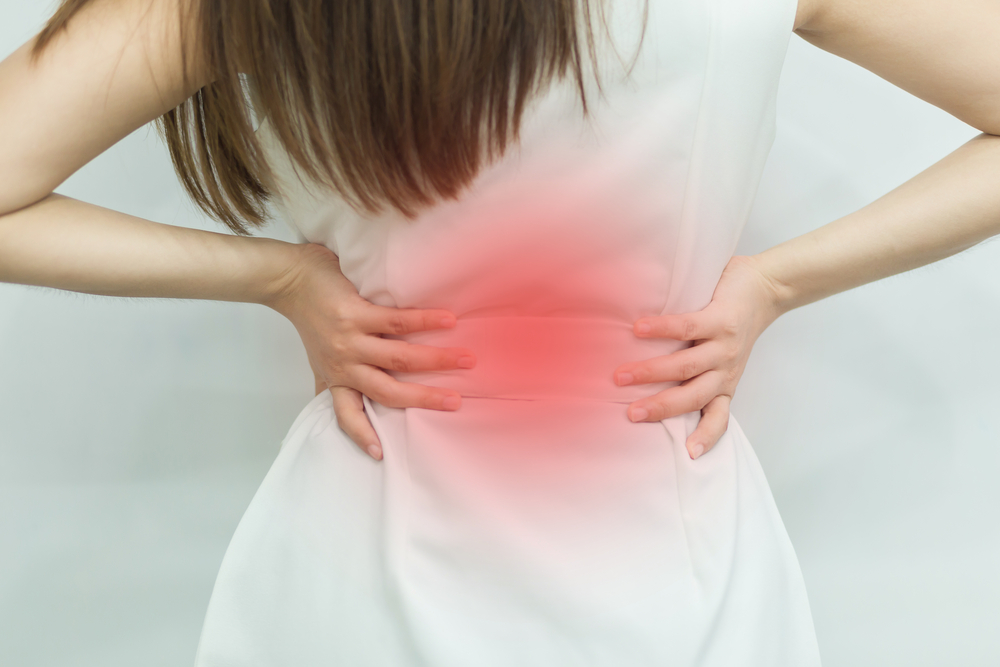 A woman in white dress feeling pain on his back