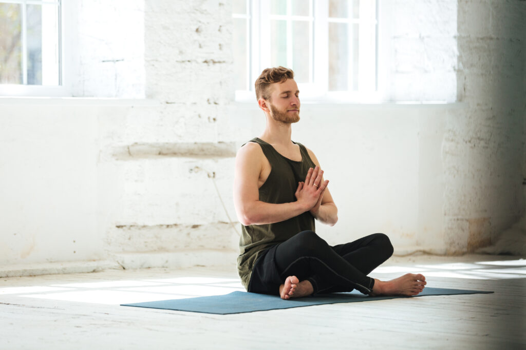 Smiling Man Meditating On Fitness Mat In The Gym